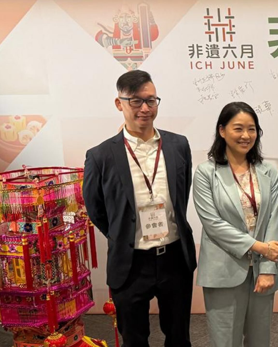 Dos asistentes posan delante del panel de ICH June durante el encuentro de Hong Kong.